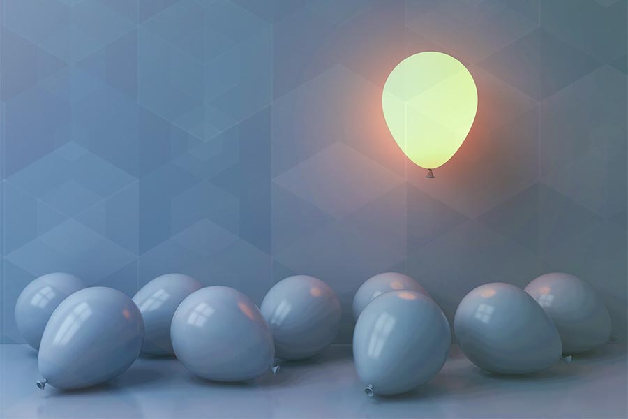 A bunch of balloons lie on the floor, grey. One glowing balloon floats above them.